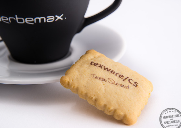 Butterkeks mit einem Logo bedruckt neben einer Tasse Cappuccino als Werbegeschenk.