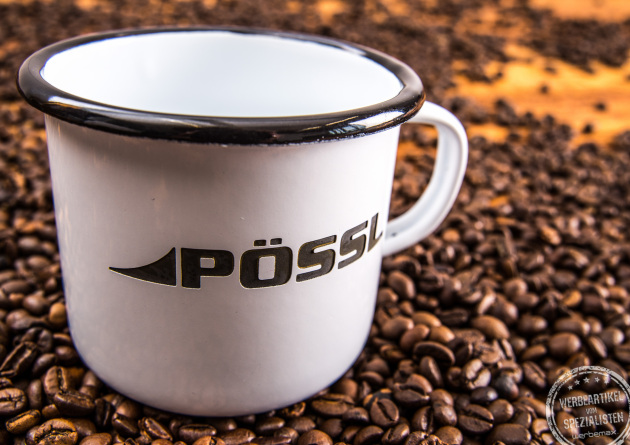 P&ouml;ssl Emaillebecher mit rusty Optik  als Werbegeschenk auf Kaffeebohnen pr&auml;sentiert.