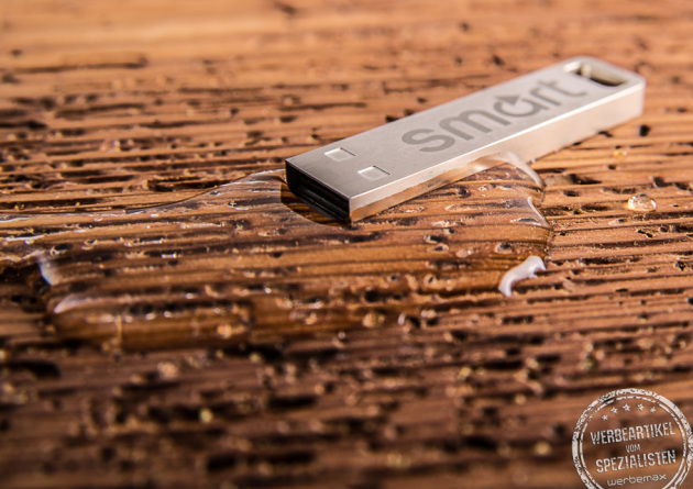 USB Stick Element auf Holzfläche liegend in silber aus Edelstahl als Werbeartikel.