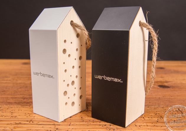 Zwei Werbemittel Insektenhotels aus Holz mit Aluminiumdach in schwarz und weiß mit Logogravur.