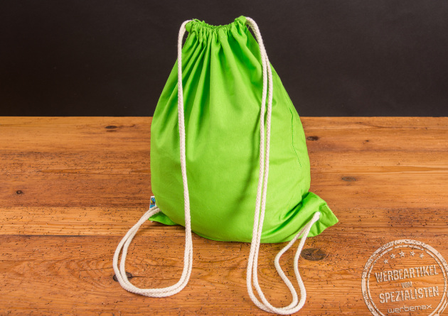 Baumwollrucksack Hanna in Hellgr&uuml;n stehend auf einem Holztisch mit naturfarbenen Baumwollkordeln
