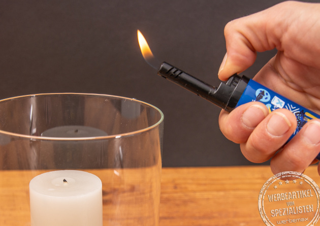 Eine Hand, die ein BIC EZ Reach Stabfeuerzeug, zum Anzünden einer Kerze hält.