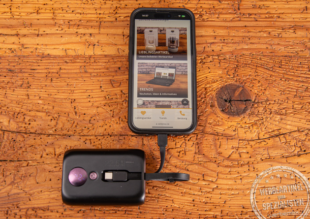 Schwarze 10.000 mAh Powerbank mit Ladestandsanzeige mit einem angehängten Apple iPhone.