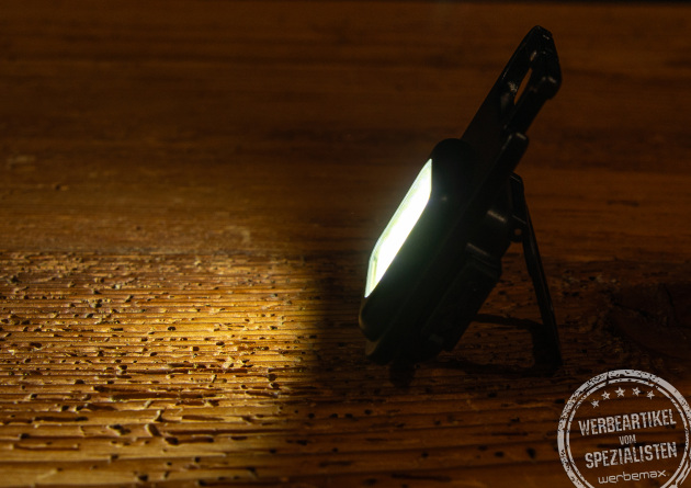 Ein Worklight, das im Dunkeln auf einer Holzplatte steht und leuchtet.