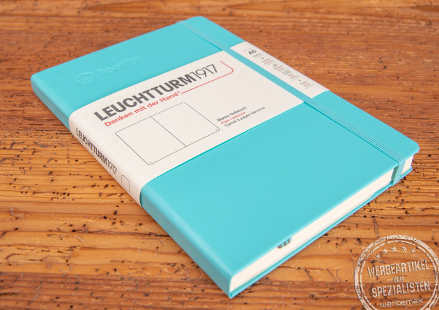 Leuchtturm1917 Notizbuch türkis mit Prägung liegend auf Holzunterlage.