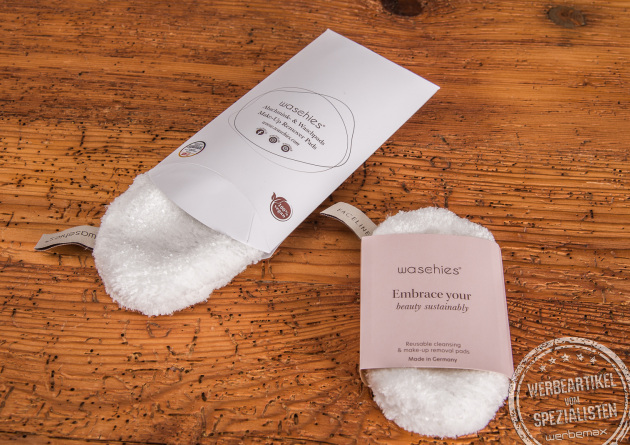 Zwei wiederverwendbare Abschminkpads Waschies mit bedruckter Kissenverpackung und Banderole als Werbeartikel.
