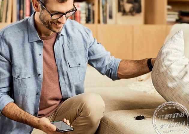 Hochwertiges Werbegeschenk - Key Finder Chipolo in schwarz auf Sofa unter Kissen.