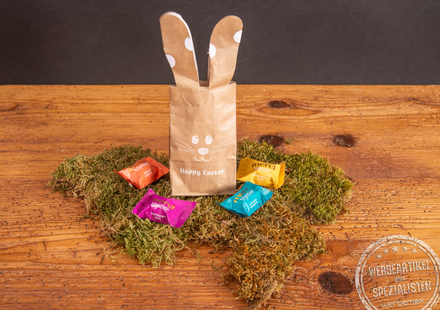 Bunny Bag Ostergeschenk gef&uuml;llt mit Merci Schokolade als Kundengeschenk im Moos auf Holztisch.