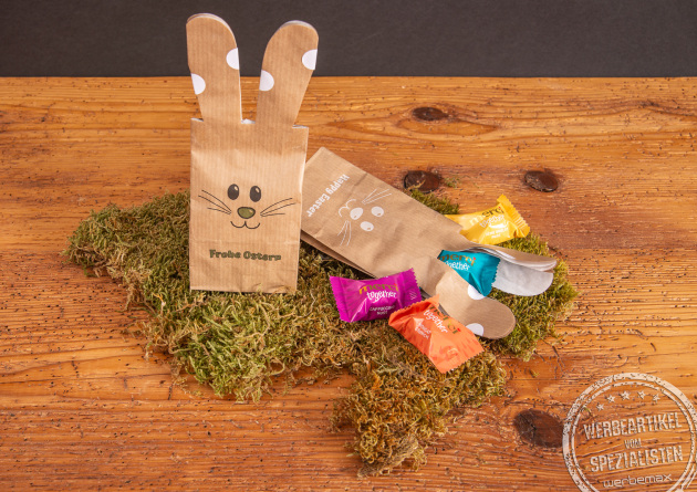 Ostert&uuml;te Bunny Bag mit S&uuml;&szlig;igkeiten von Merci als Werbegeschenk im Moos auf Holztischplatte..