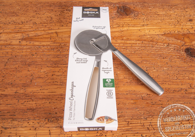 Mitarbeitergeschenk Pizzaroller Boska in einer sch&ouml;nen Kartonverpackung. Mit Lasergravur als langlebiger Werbeartikel unverzichtbar in jeder K&uuml;che. Auf Holztisch