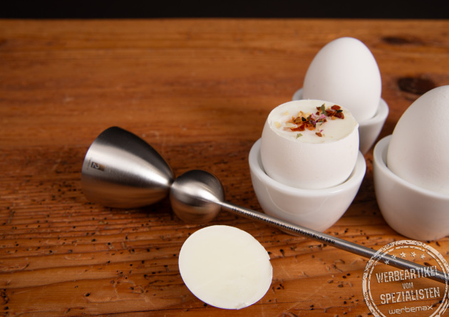Detailaufnahme des Clack Eier&ouml;ffners nach der Anwendung &ndash; ge&ouml;ffnetes Fr&uuml;hst&uuml;cksei mit Kr&auml;utern serviert.