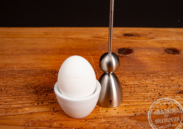 Clack Eierschalensollbruchstellenverursacher neben gekochten Ei im Eierbecher.