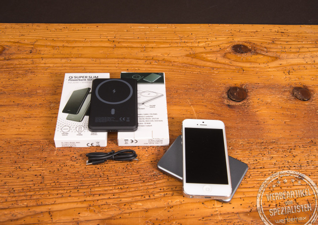Powerbank mit Logo und MagSafe-Funktion, abgebildet mit Smartphone, Verpackung und Ladekabel auf einem Holztisch