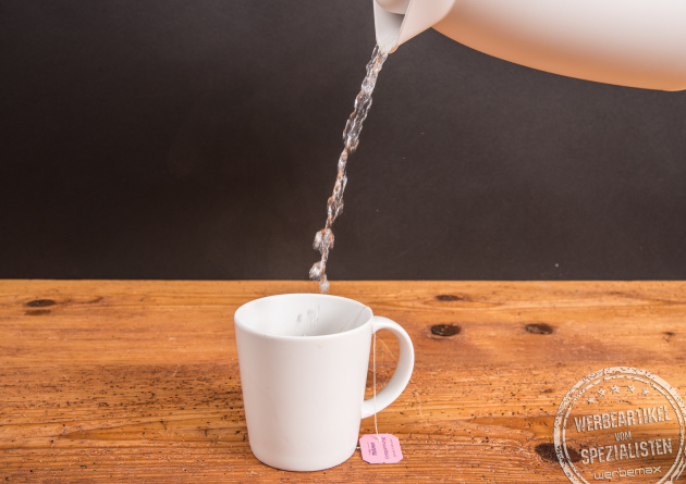 Wei&szlig;er Einfach Becher aus Porzellan von SND mit Teebeutel, wird mit hei&szlig;em Wasser aufgef&uuml;llt.