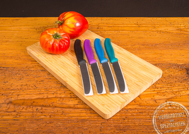 Bunte Victorinox Tomatenmesser auf Schneidebrett mit frischen Tomaten – langlebige Messer mit Logogravur.