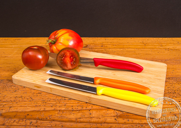 Victorinox Tomatenmesser mit Gravur auf Holzbrett neben Tomaten – perfektes Werbemittel für Küche und Genuss.