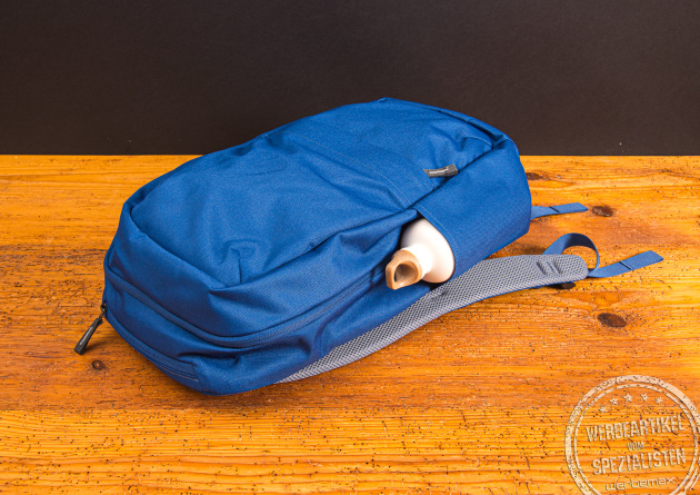 Deuter Rucksack DI Pack 23 mit SIGG Flasche in der praktischen Seitentasche. Liegen auf einem Holztisch fotografiert. Modernes Design, dass unisex gerne getragen und kombiniert wird.  Mit individuellem Logostick ein schönes Werbegeschenk.