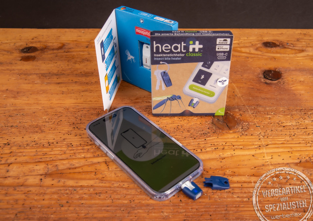 heat it Insektenstichheiler am Smartphone mit Verpackung – chemiefreies Werbegeschenk für Outdoor, Reisen und Sommer.