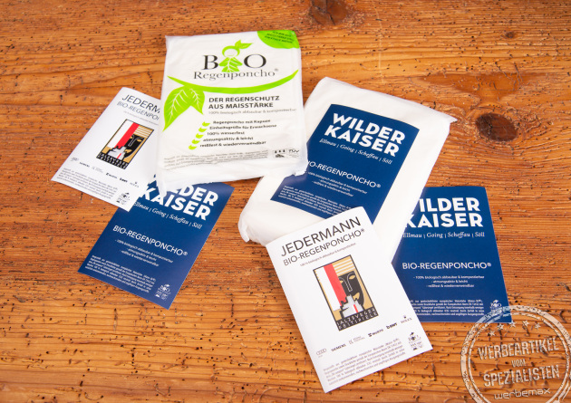 Individuell gestaltete Verpackungen biologisch abbaubarer Regenponchos aus Maisstärke – nachhaltige Regencapes mit Logo als umweltfreundliche Werbegeschenke für Events, Festivals und Tourismus von werbemax.