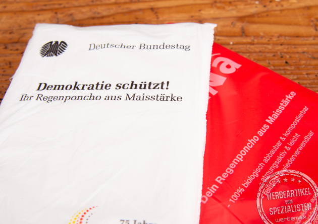 Detailaufnahme individuell bedruckter Verpackungen biologisch abbaubarer Regenponchos aus Maisstärke – nachhaltige Werbeartikel mit Logo für Events, Festivals und Institutionen von werbemax