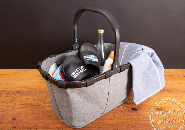 Reisenthel Carrybag Twist Silver in Grau, bef&uuml;llt mit Sommerutensilien wie Handtuch, Sandalen und Getr&auml;nk &ndash; stilvoller Einkaufskorb als hochwertiges Werbegeschenk oder Mitarbeiterpr&auml;sent.
