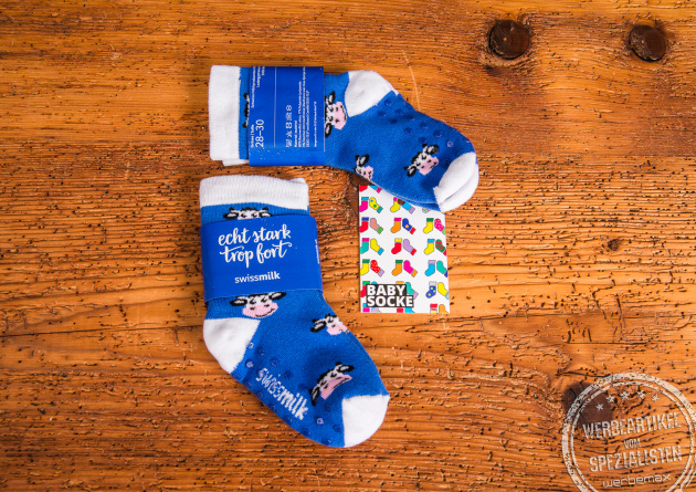 Individuell gestaltete Babysocken als persönliches Geschenk zur Geburt mit Ihrem Firmenlogo. Ein Paar Babysocken in blau mit weißen Zehen und Fersen mit lustigen Kuhmotiv. Mit Rutschnoppen.