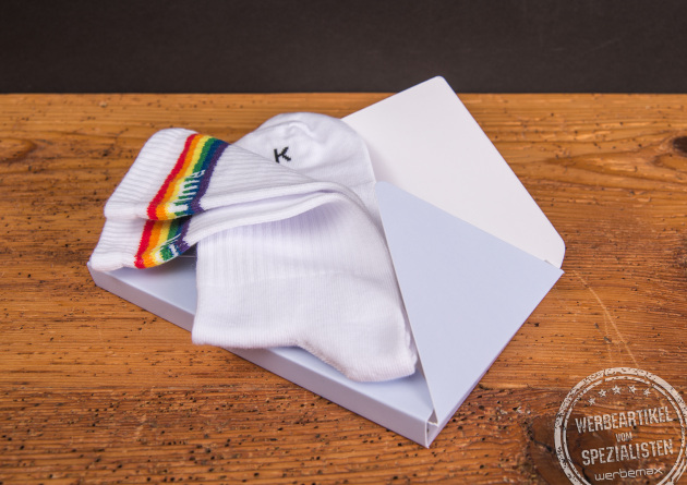 Weiße Tennissocken mit Regenbogenstreifen in einer Mailingbox – kreativer Werbeartikel oder Kundenmailing mit persönlicher Note.
