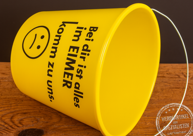 Gelber Kunststoff-Eimer mit dem frechen Aufdruck ‚Bei dir ist alles im Eimer – komm zu uns‘, genutzt als aufmerksamkeitsstarker Werbeartikel für Azubimessen.