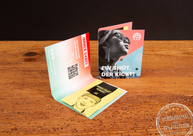 Werbekarte Midi Just Spices mit Avocado Topping als individuell bedruckter Werbeartikel; ge&ouml;ffnete Gew&uuml;rzkarten als moderne Messe-Giveaways auf Holztisch, ideal zum Werbeartikel bedrucken.