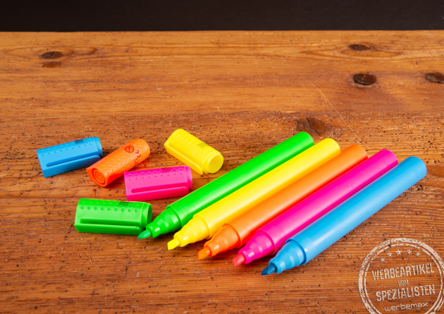 Ge&ouml;ffnete Jumbo Textmarker im XL-Format in leuchtenden Farben als Riechstifte auf Holztisch &ndash; kreative Giveaway-Idee f&uuml;r Messen und Bewerbermarketing mit gro&szlig;er Werbefl&auml;che und starkem Markenauftritt.