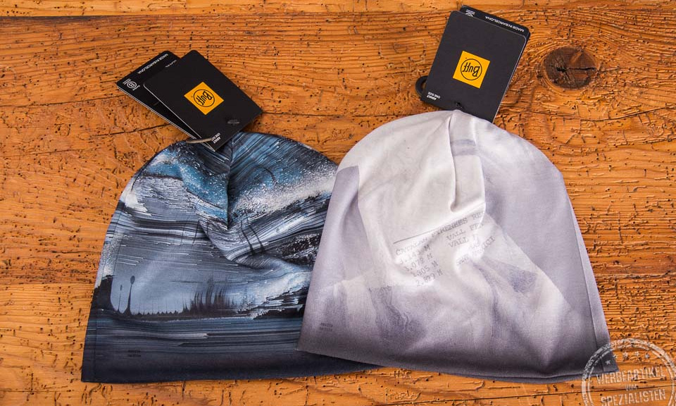 Zwei d&uuml;nne M&uuml;tzen von BUFF im 4c-Druck auf einem Holztisch gelegt mit dem original BUFF Label als Kundengeschenk