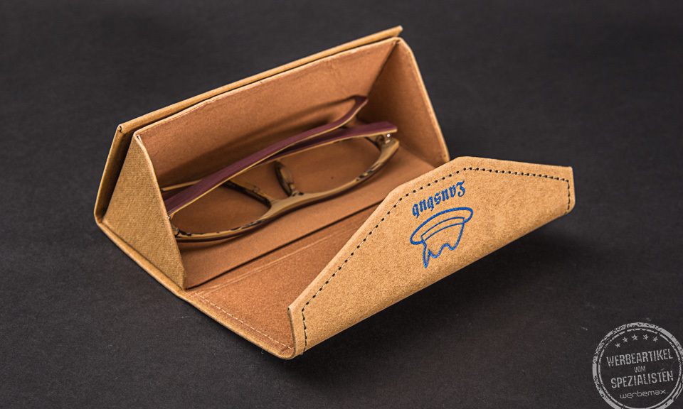 Ein Brillenetui aus Kraftpapier mit Logodruck als Werbegeschenk auf schwarzem Hintergrund.