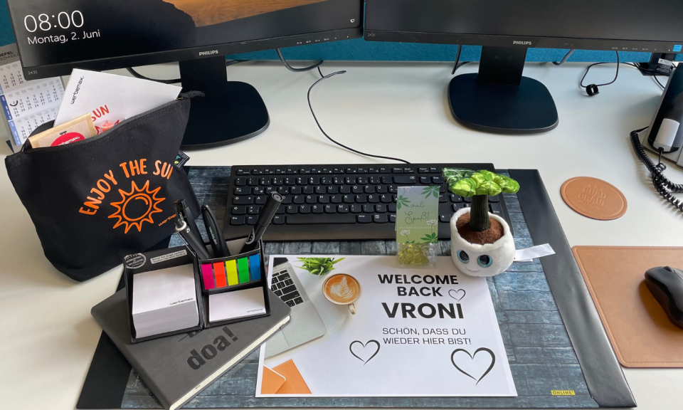 werbemax Schreibtisch mit Onboarding-Werbeartikel wie z.B. ein Schmoozie Evergreenies Displaycleaner, Stifte, Süßigkeiten im Blockbeutel, Kosmetiktasche mit Newkee-Sonnencreme 