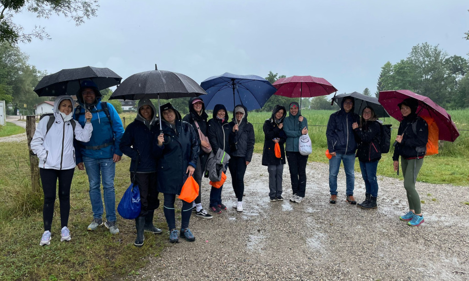 Das werbemax Team im Regen mit Regenschirmen vor Beginn der Alz Flo&szlig;fahrt.
