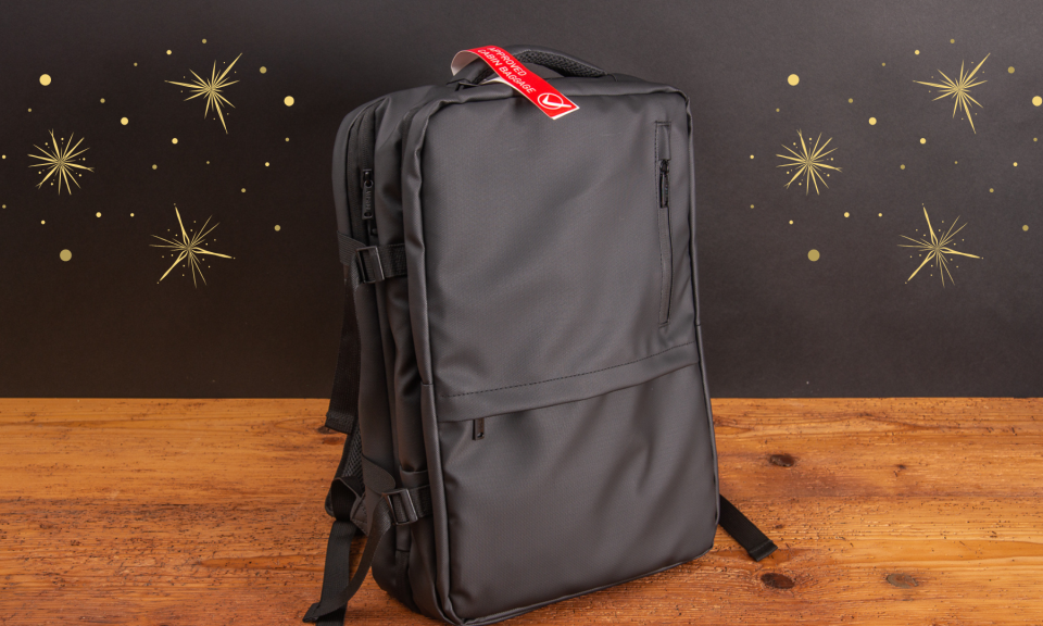 Schwarzer VASAD Underseater Rucksack auf Holztisch, vor dunklem Hintergrund mit goldenen Sternen – modernes Weihnachtsgeschenk für Mitarbeiter.