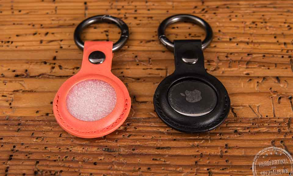 Apple Air Tag mit Anh&auml;nger-cover in orange und schwarz als Werbegeschenk
