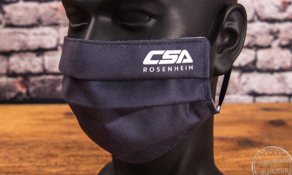 Mund-Nasen-Maske in schwarz als Werbeartikel mit Logo CSA Rosenheim an der Seite bedruckt. 