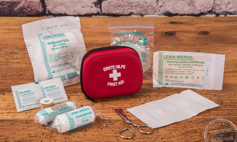 Rotes Erste Hilfe Set als Werbeartikel mit Klebeband, Schere, Fixierbinde, Wundschnellverband und Alkoholtupfer 