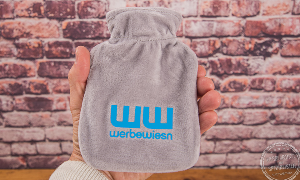 Wärmflasche in grau in der Hand gehalten mit Logo WW bedruckt