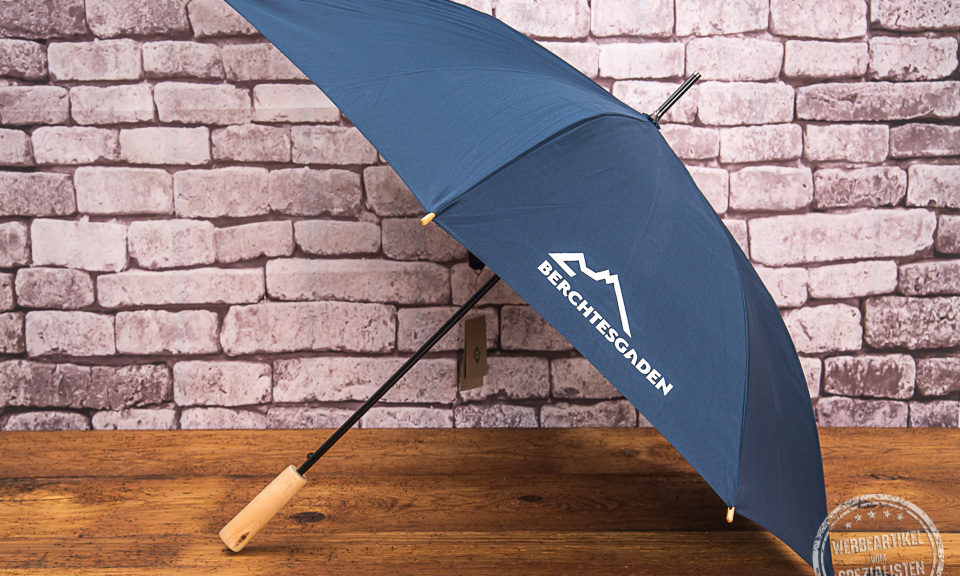 blauer Stockschirm mit wei&szlig;em Logodruck auf einem Keil