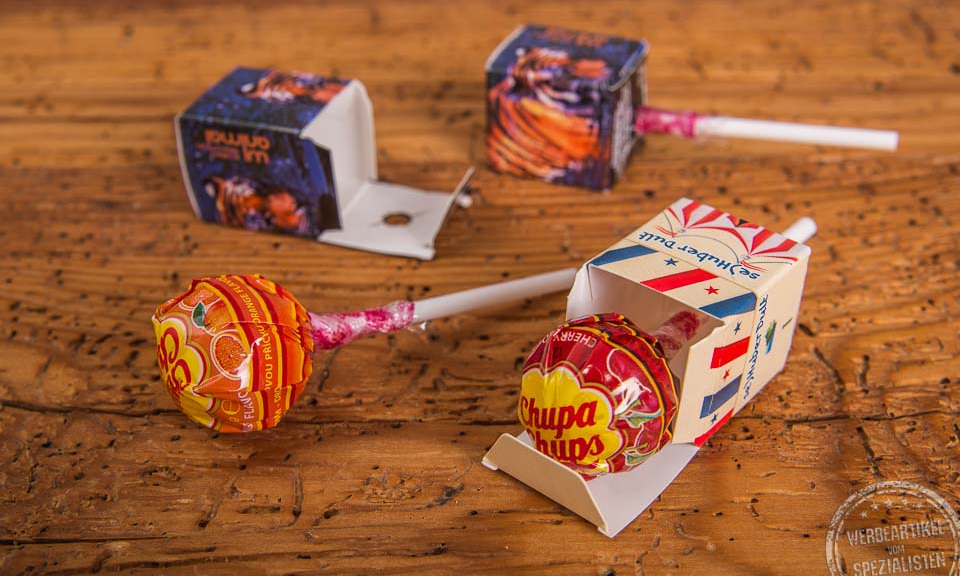 Kinderwerbeartikel Chupa Chups in bedruckter Werbebox auf Holztischplatte.