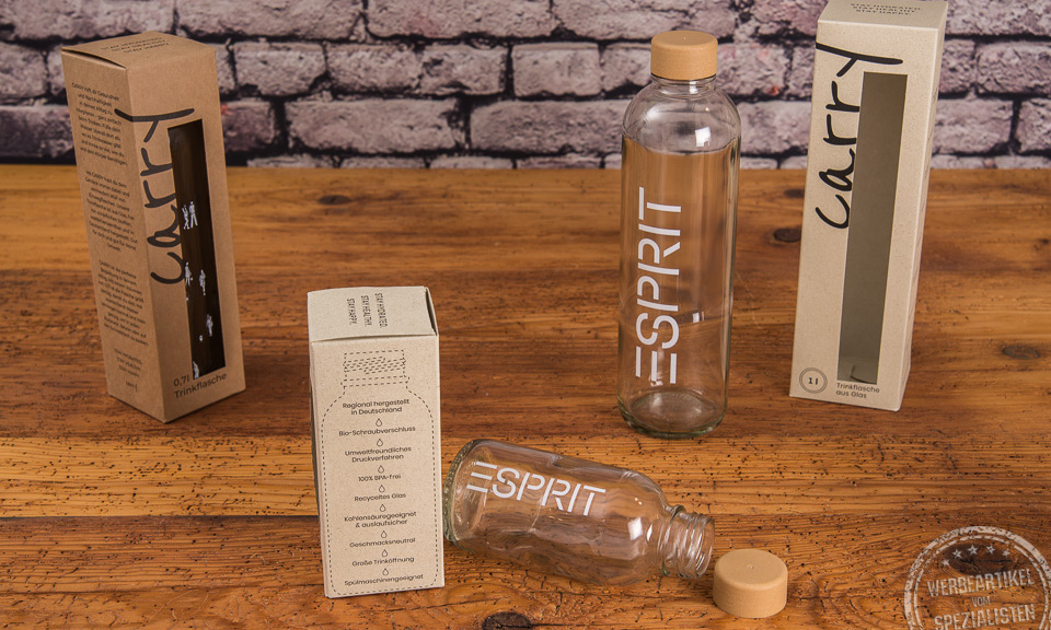 Glasflasche mit Logo als Mitarbeiter- und Kundengeschenk in verschiedenen Größen auf Holztisch.