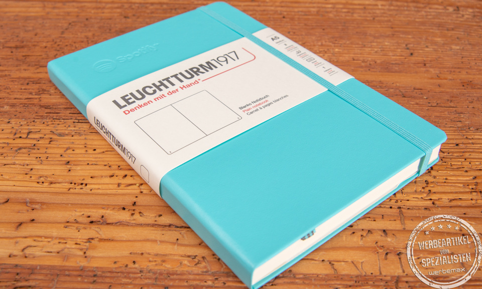 Leuchtturm1917 Notizbuch türkis mit Prägung liegend auf Holzunterlage.