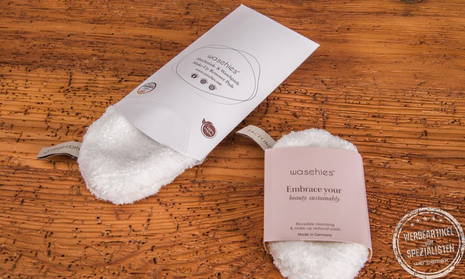 Zwei wiederverwendbare Abschminkpads Waschies mit bedruckter Kissenverpackung und Banderole als Werbeartikel.