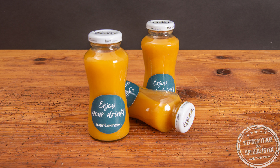 Drei Glasflaschen mit gelbem Smoothie und individuellem Werbe-Etikett als Giveaway.