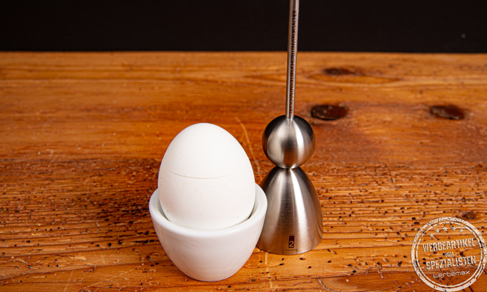 Clack Eierschalensollbruchstellenverursacher neben gekochten Ei im Eierbecher.