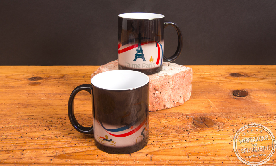 Zwei Kaffeetassen mit Magic-Farbwechseldruck und Paris-Motiv im Übergang – individuelle Werbeartikel Tassen mit Thermoeffekt von werbemax.