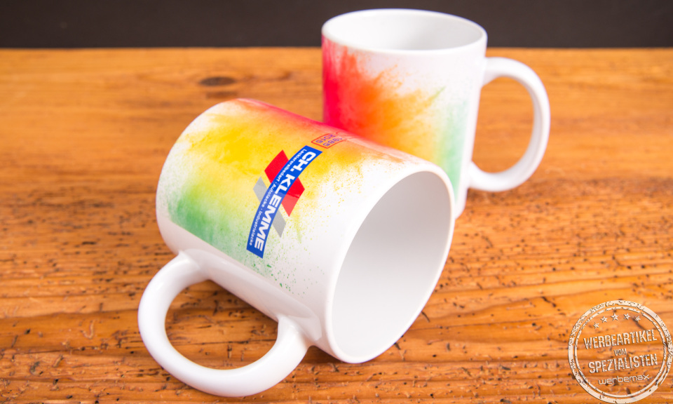 Zwei wei&szlig;e Tassen mit farbenfrohem Sublimationsdruck und Firmenlogo &ndash; individuell gestaltete Werbeartikel Tassen mit Regenbogendesign.