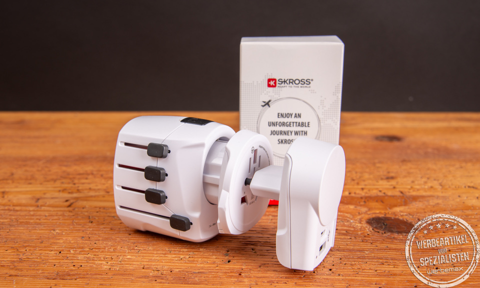 SKROSS PRO+USB Reiseadapter mit Verpackung auf Holztisch – ideales Werbegeschenk für internationale Geschäftsreisen.