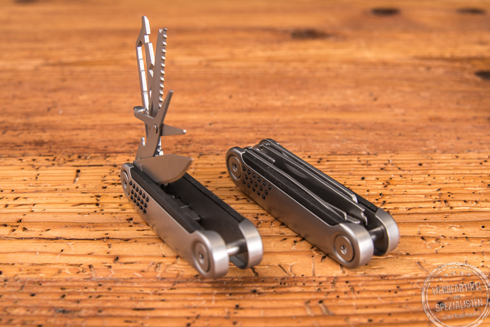 Zwei Taschenmesser als Werbegeschenk liegend auf Holzfläche, ein Taschenmesser ist geöffnet.